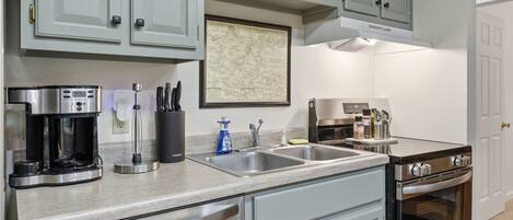 A kitchen with stainless steel appliances, a coffee maker, a sink, and a stove.