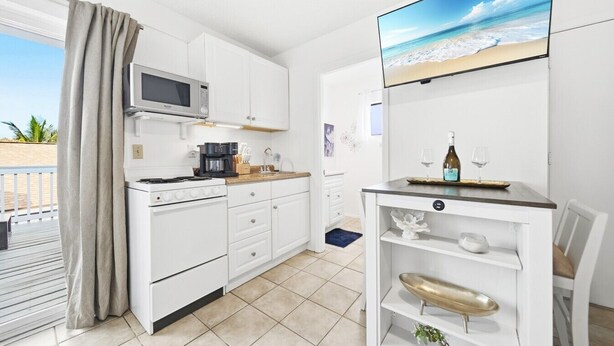 A compact kitchen with white cabinets, a microwave, a coffee maker, and a small dining area with a table and chairs. - Beach Rd, 300ft to Beach Access & 500ft to Siesta Key Village, Studio (Siesta Key)