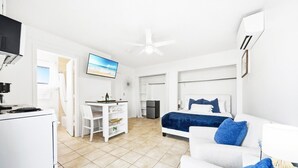 A modern hotel room with a bed, a white sofa, a desk with a chair, a television, and a ceiling fan. - Beach Rd, 300ft to Beach Access & 500ft to Siesta Key Village, Studio (Siesta Key)
