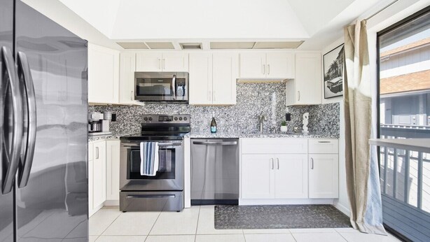 A modern kitchen with white cabinets, stainless steel appliances, and a granite countertop.