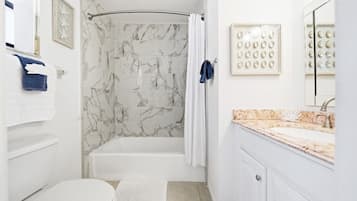 Une salle de bain équipée d’une baignoire, d’une douche, de toilettes et d’un meuble-lavabo avec un évier.