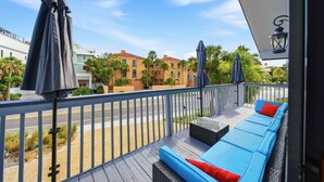 A balcony with a blue sofa and red cushions, a metal railing, and umbrellas.