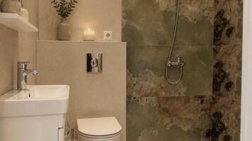 A modern bathroom with a shower, toilet, sink, and decorative plants.