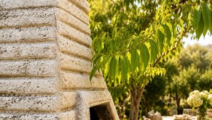 A stone barbecue grill with a chimney, surrounded by outdoor dining tables and chairs. - Guest House Fjola (Donji Štoj)