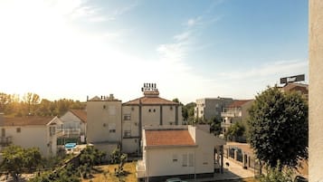 A balcony with a view of a residential area, including houses and a swimming pool.