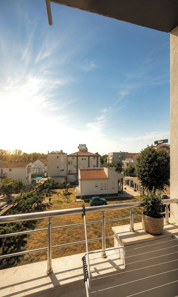 A balcony with a view of a residential area, including houses and a swimming pool.