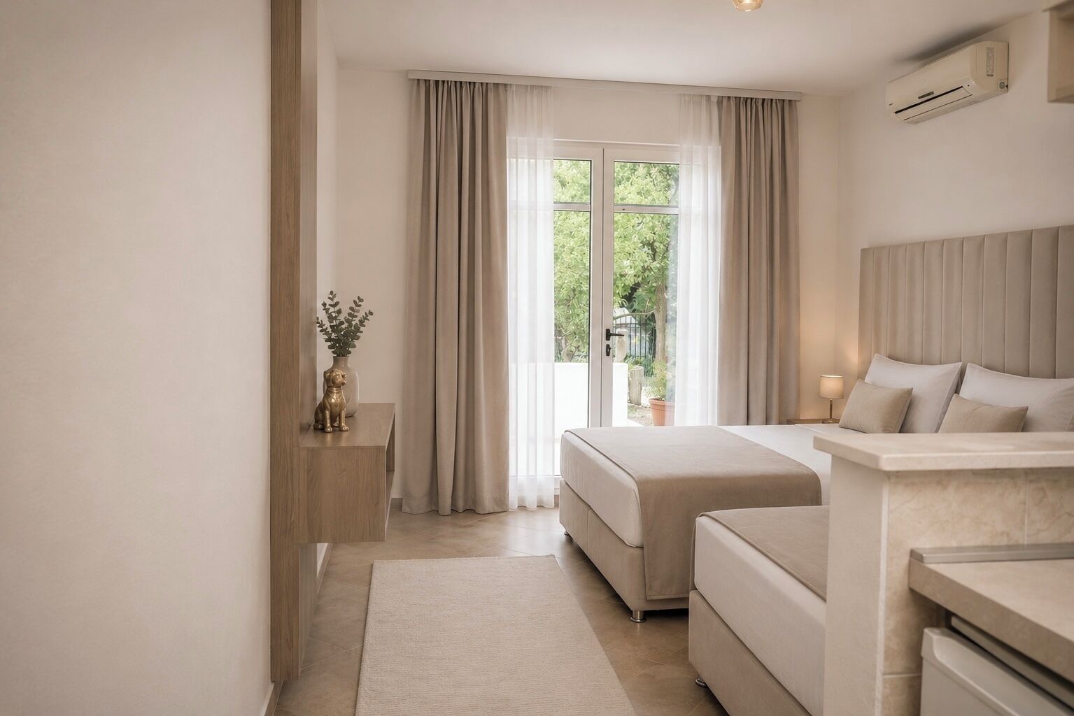 A modern bedroom with a bed, bedside table, and a view of greenery outside.