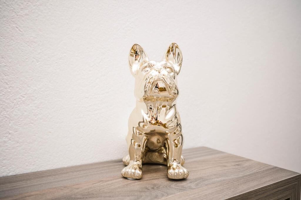 A gold-colored dog figurine on a wooden surface.