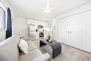Ein modernes Wohnzimmer mit einer Couch, einem Couchtisch und einer Küche im Hintergrund.