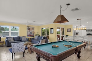 A living room with a pool table, sofas, and a dining area. - Salty Skies : 4-bedroom - Pool - Dock - walking distance from Sombrero Beach (Marathon)