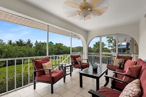 Ein geräumiger Balkon mit Deckenventilator, roten Polsterstühlen und einem Tisch mit Blumenvase.