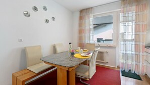 A compact living space with a dining table, two chairs, a sofa, and a radiator. - Quiet Riverside Wallbach Apartment with Terrace, AC, Washer, and Rhine View (Bad Säckingen)