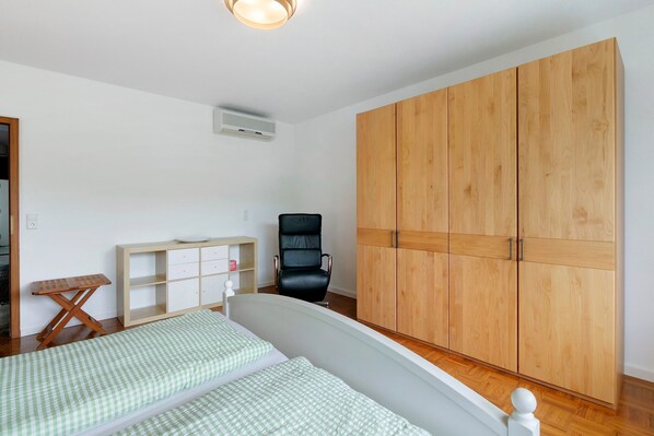 A bedroom with a bed, a desk, a chair, and a wardrobe.