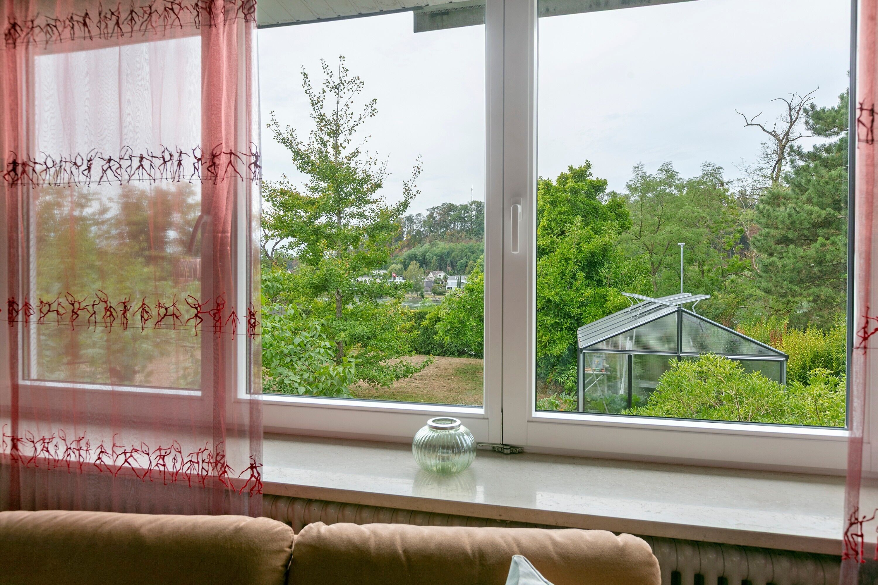 Ein Fenster mit Blick auf ein Gewächshaus und einen klaren Himmel.