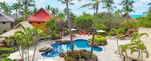 A resort with a swimming pool, palm trees, and a red-roofed building. - 2-bedroom/bath resort in marvelous Kailua-Kona (Kailua-Kona)