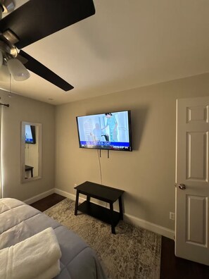 A bedroom with a bed, a television mounted on the wall, a ceiling fan, and a door. - Awesome 3-bedroom house with AC in delightful Chattanooga (Chattanooga)
