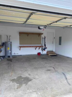 A garage with a water heater, a wooden bench, and a door. - Awesome 3-bedroom house with AC in delightful Chattanooga (Chattanooga)
