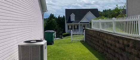 A residential property with a well-maintained lawn, a white picket fence, and a house with a dark roof.