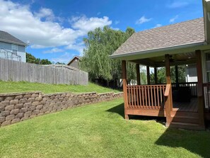Ein Wohnhaus mit einer Holzterrasse, einer Steinmauer und einem Rasen.