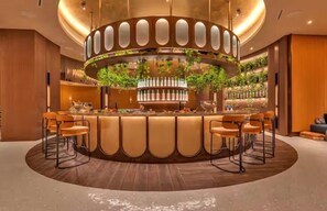 Eine Bar mit einer runden Bar, mehreren Hockern und einem zentralen Dekorationselement.