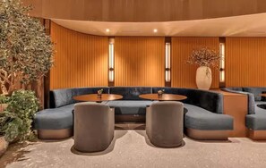 A modern lounge area with a curved sofa, round tables, and a large vase of flowers. - 1-bedroom studio in adorable Miami with AC and fitness room (Miami)