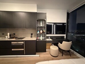 A modern kitchen with dark cabinetry, a built-in oven, and a small dining area with a white chair. - 1-bedroom studio in adorable Miami with AC and fitness room (Miami)