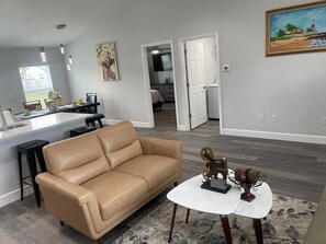 A modern living room with a beige sofa, a small white table, and a decorative metal sculpture.