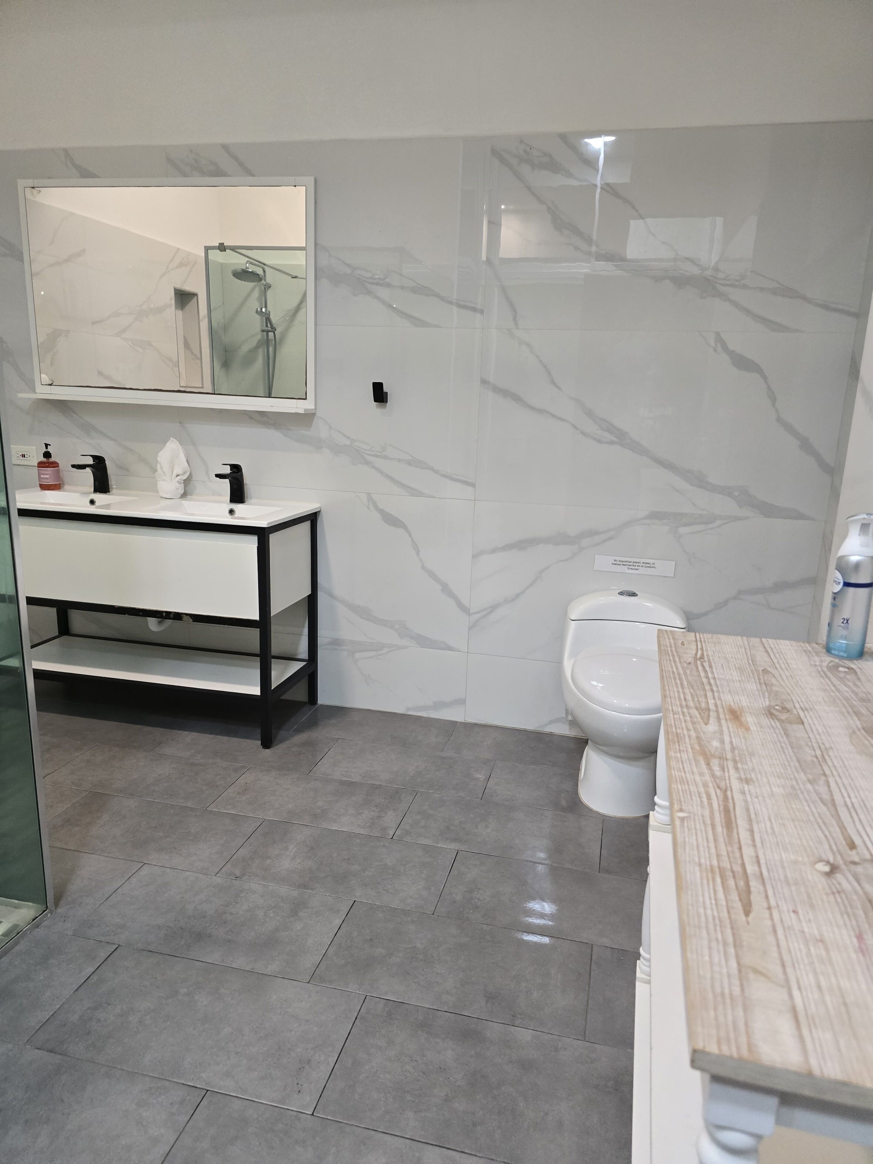 A modern bathroom with a white vanity, a glass shower enclosure, and a toilet.
