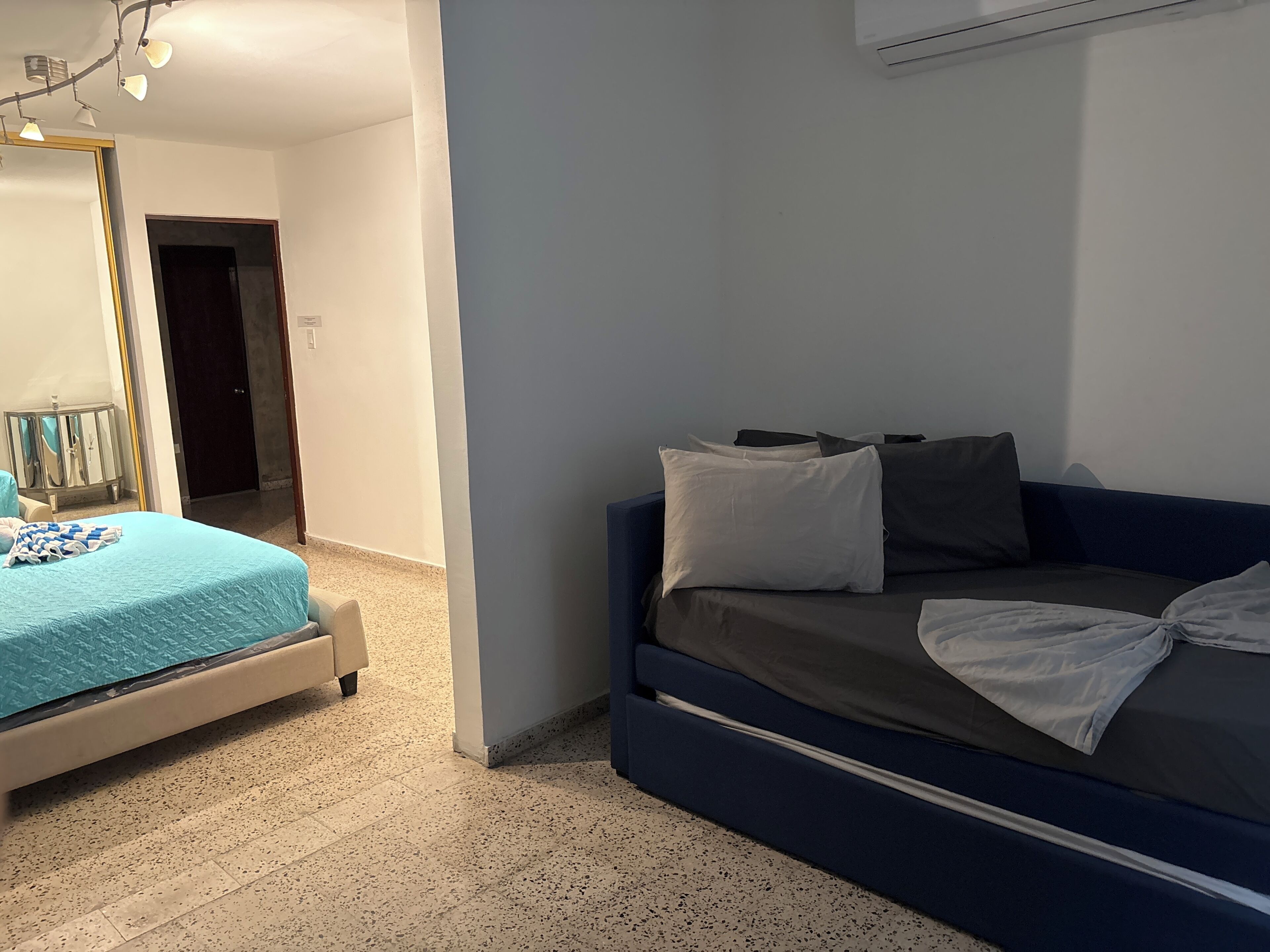 Ein Schlafzimmer mit einem Bett, einem Schlafsofa und einem Spiegel.