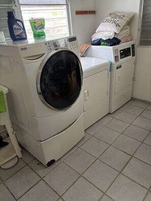 A laundry area with a front-loading washing machine, a dryer, and a stack of folded clothes.
