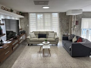 A living room with a sofa, a coffee table, and a TV.