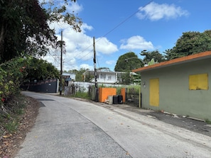 A quiet street with a building featuring a yellow door, surrounded by greenery and a clear sky.