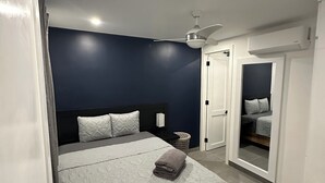 Een slaapkamer met een bed, nachtkastje en plafondventilator.