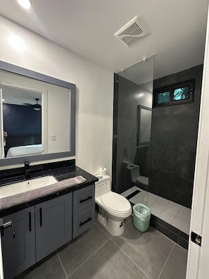 Un baño moderno con inodoro, lavamanos y zona de ducha.