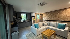 Een moderne woonruimte met een keuken, een zithoek en een houten salontafel.