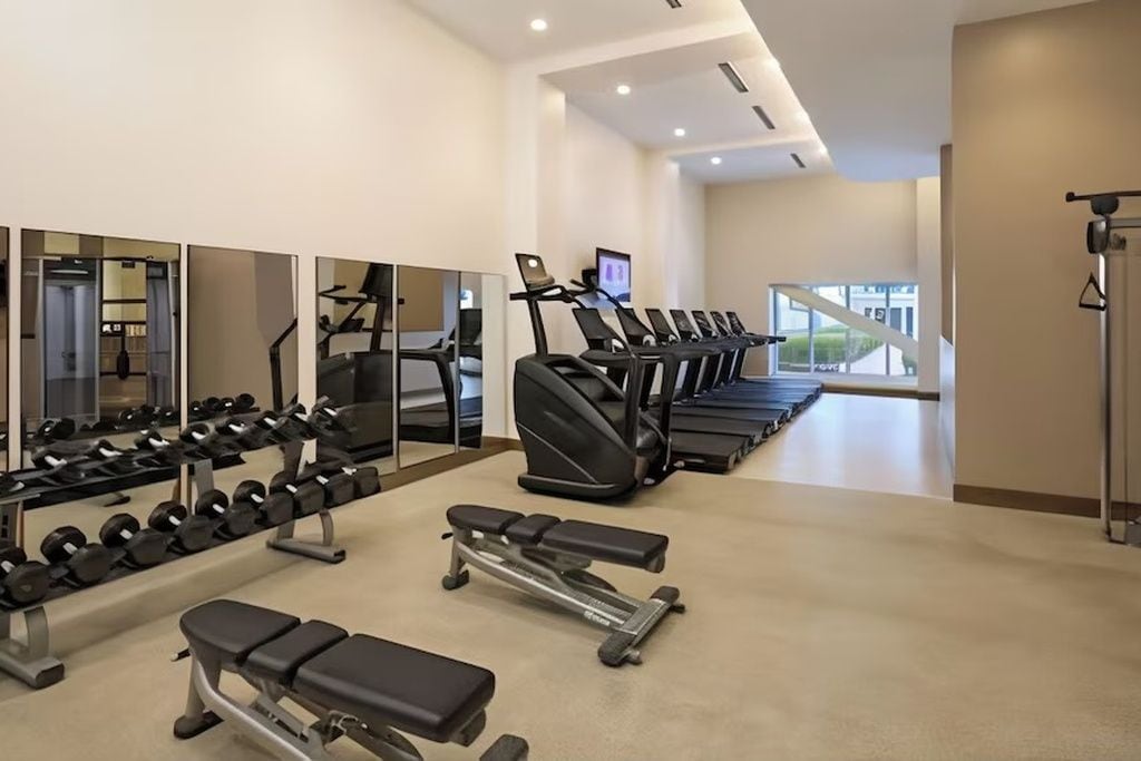 A gym with treadmills, dumbbells, and benches.