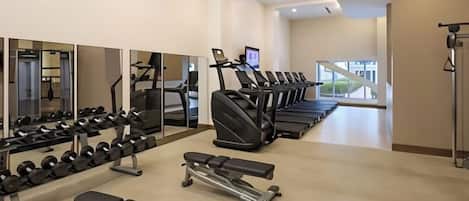 A gym with treadmills, dumbbells, and benches.