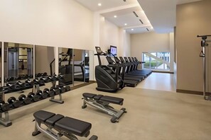 Una palestra con tapis roulant, manubri e panche.