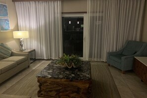 A living room with a sofa, a coffee table with a plant, a lamp, and a chair. - Outstanding apartment at Dawn Beach Club, JW Marriott Resort, Beach and Spa (oyster pond)
