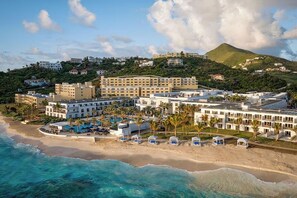 Ein Küstenhotel mit mehreren Gebäuden, einem Strand und einem Berg im Hintergrund.
