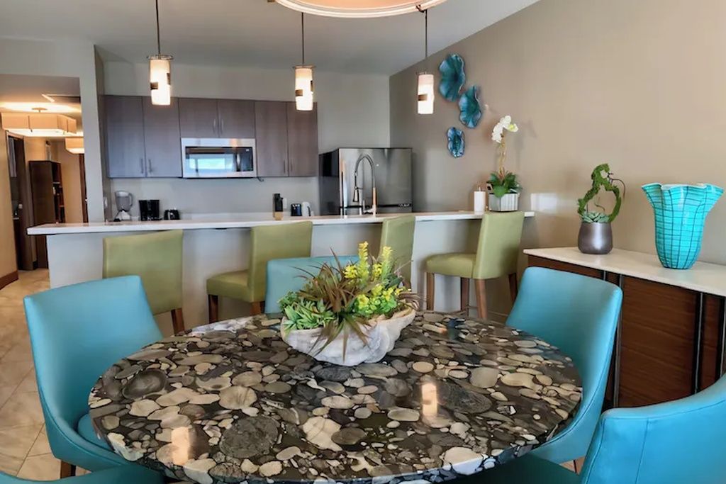 Una cocina moderna con una isla central, taburetes de bar e iluminación colgante.