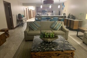 Una sala de estar con un sofá, una mesa de centro y una cocina al fondo.
