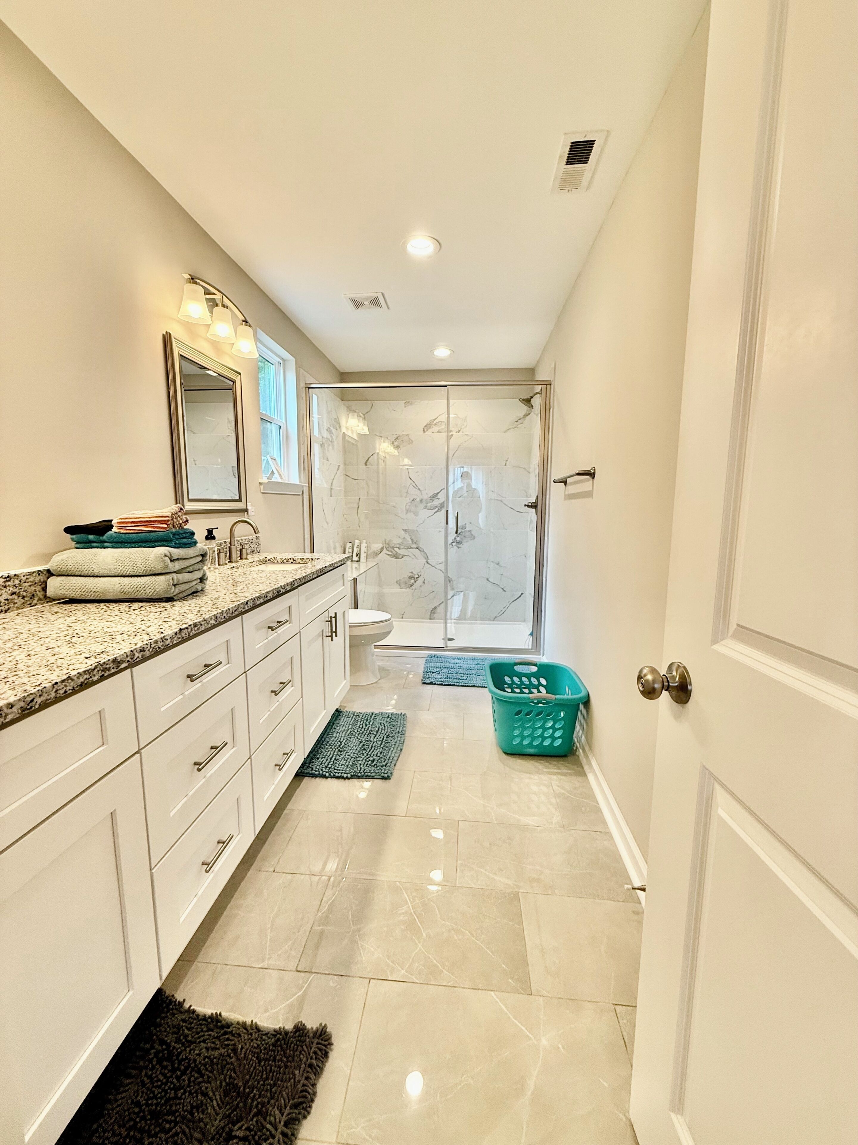 A modern bathroom with a marble shower, a sink with a mirror, and a toilet.