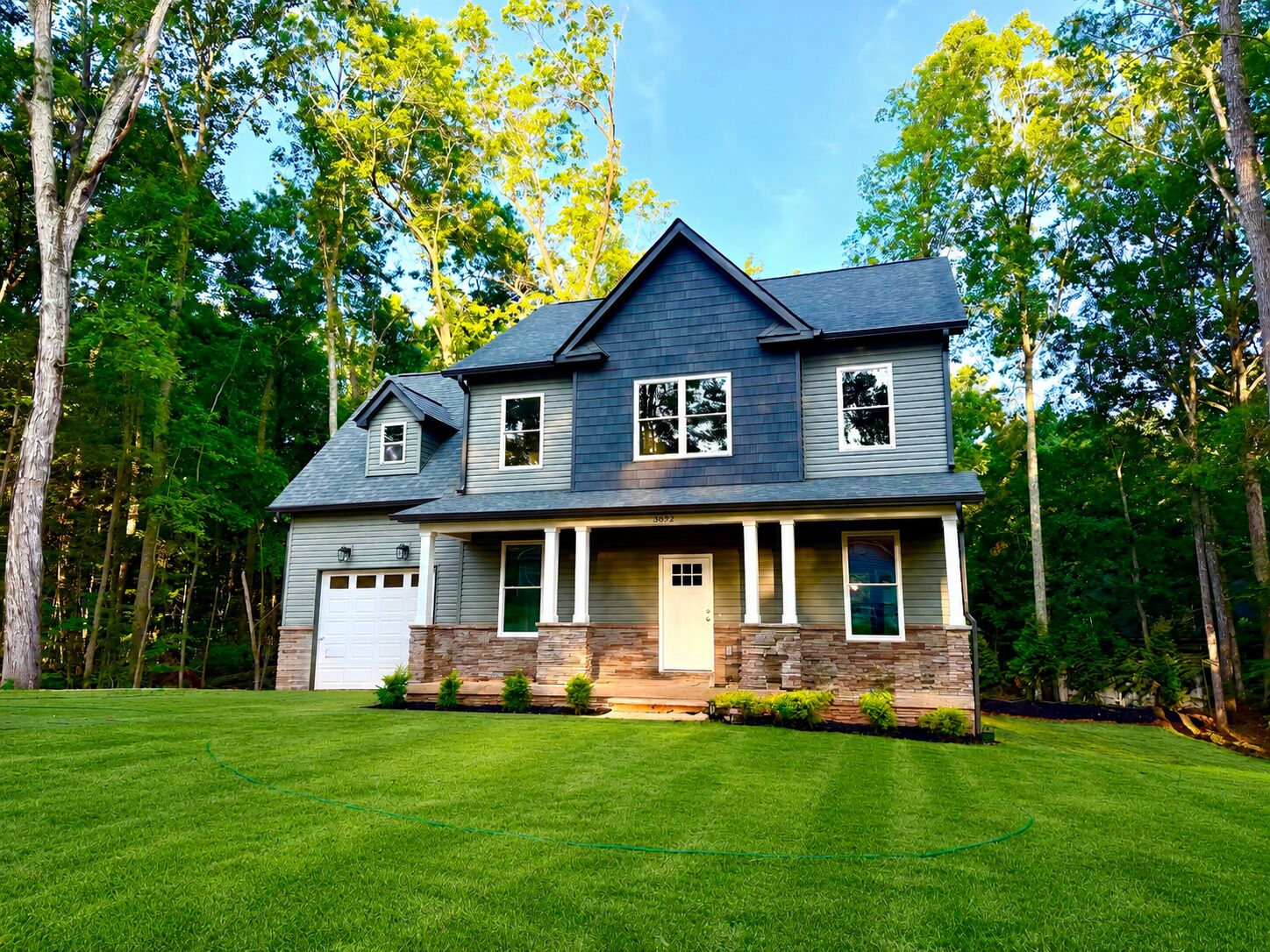 A two-story house with a garage, a front porch, and a well-maintained lawn.