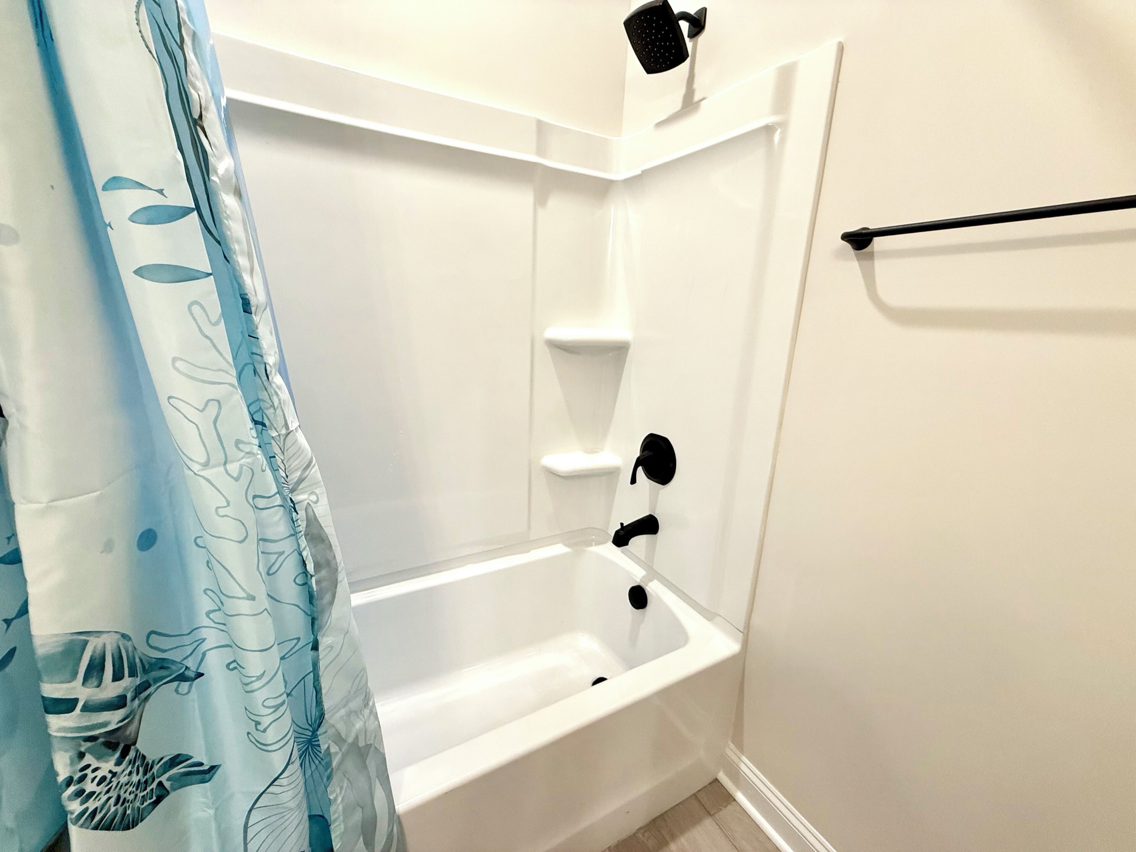 Baño con bañera blanca, ducha y perchero.