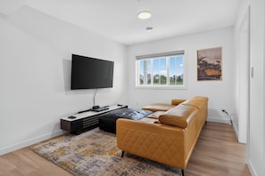 A modern living room with a flat-screen TV, a sofa, a window, and a painting. - # Spacious 2 Bedroom in Southwest Edmonton (Edmonton)