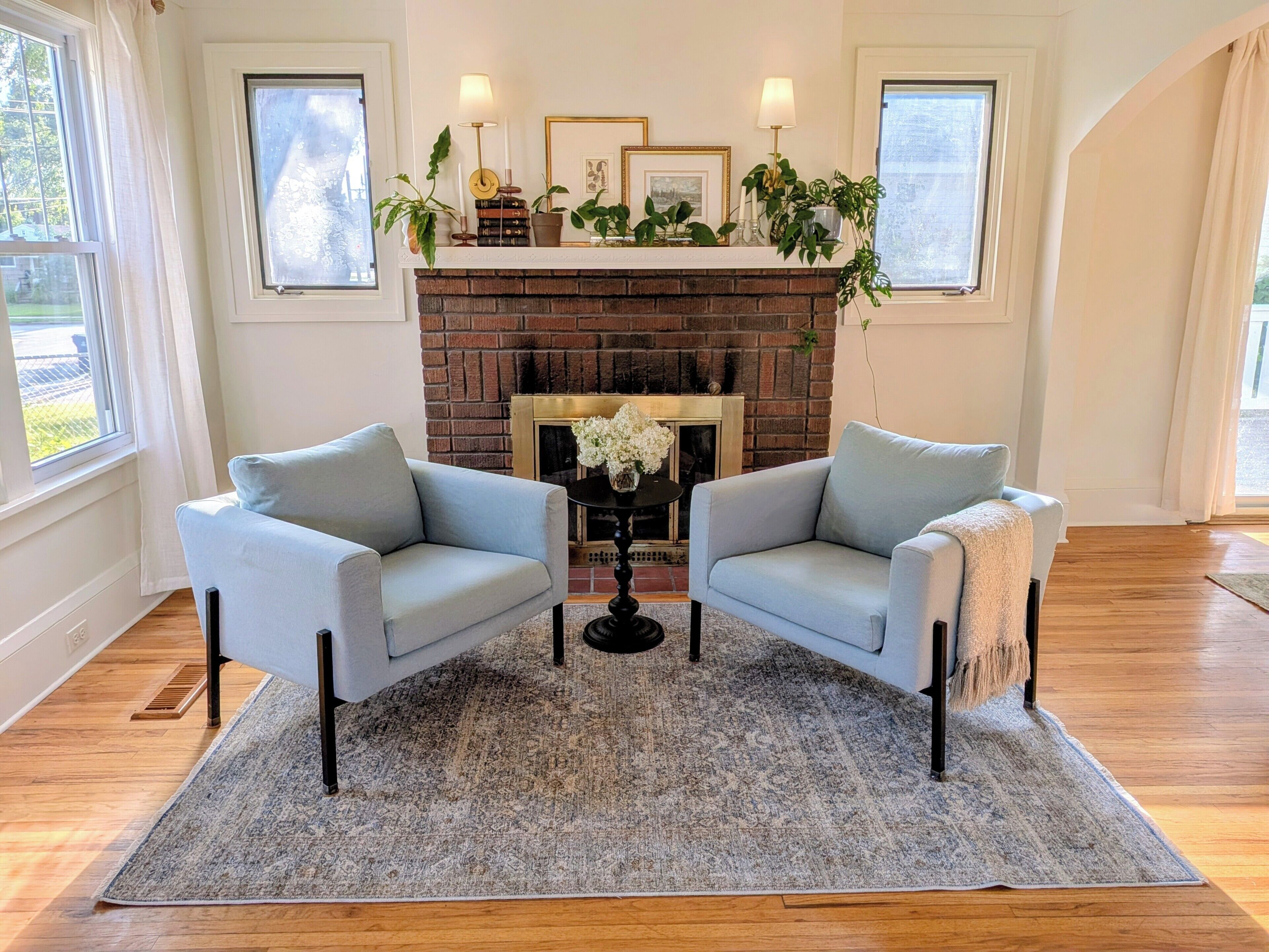 Un salon avec deux fauteuils, une cheminée et un tapis.