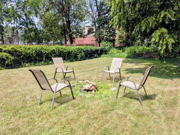 An outdoor seating area with four chairs arranged around a central fire pit.