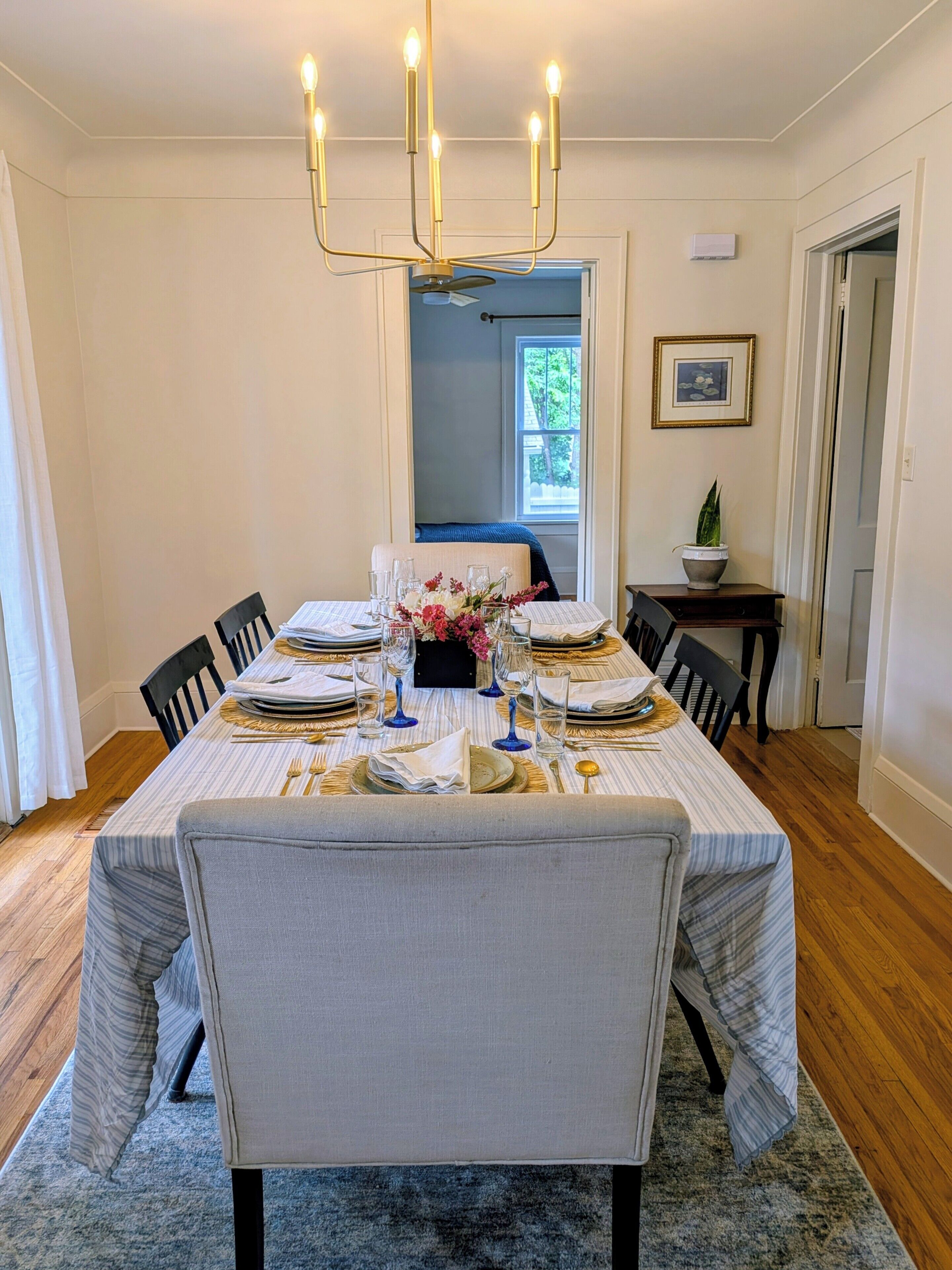Comedor con una mesa dispuesta para cuatro personas, un candelabro y una silla azul al fondo.