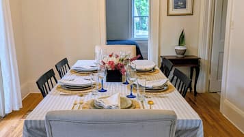 Comedor con una mesa dispuesta para cuatro personas, un candelabro y una silla azul al fondo.